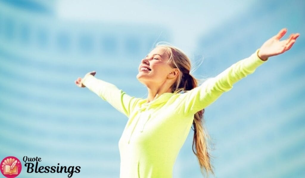 Woman smiling with open arms in bright sunlight, expressing joy and freedom.